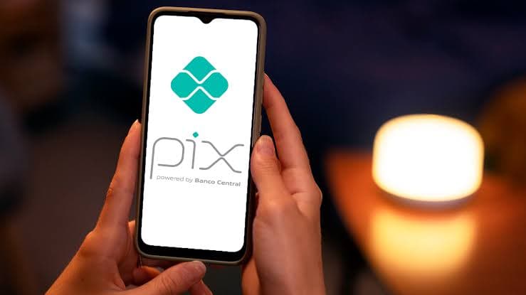 Mão fazendo um Pix no celular para pagar um funcionário