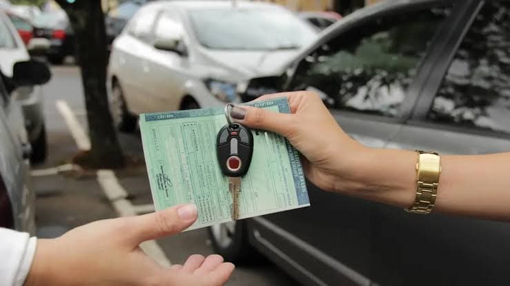 Chaves de carro sendo entregues ao comprador com o documento de venda